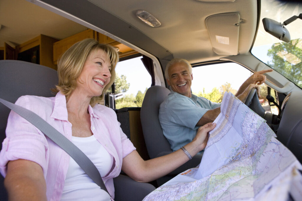 Woman with map in motor home, next to husband, smiling, low angle view.